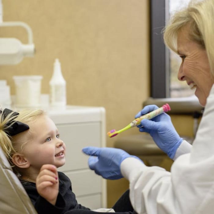 dentist brushing little girl's teeth